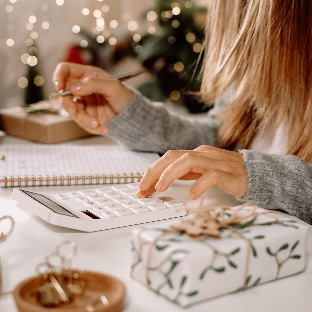 woman calculating cost of holiday gifts on calculator